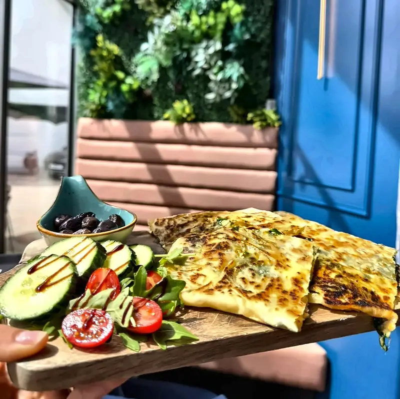 Gözleme mit Kräuterfüllung, dazu Gurke, Tomate und Avocado auf einem Holzbrett