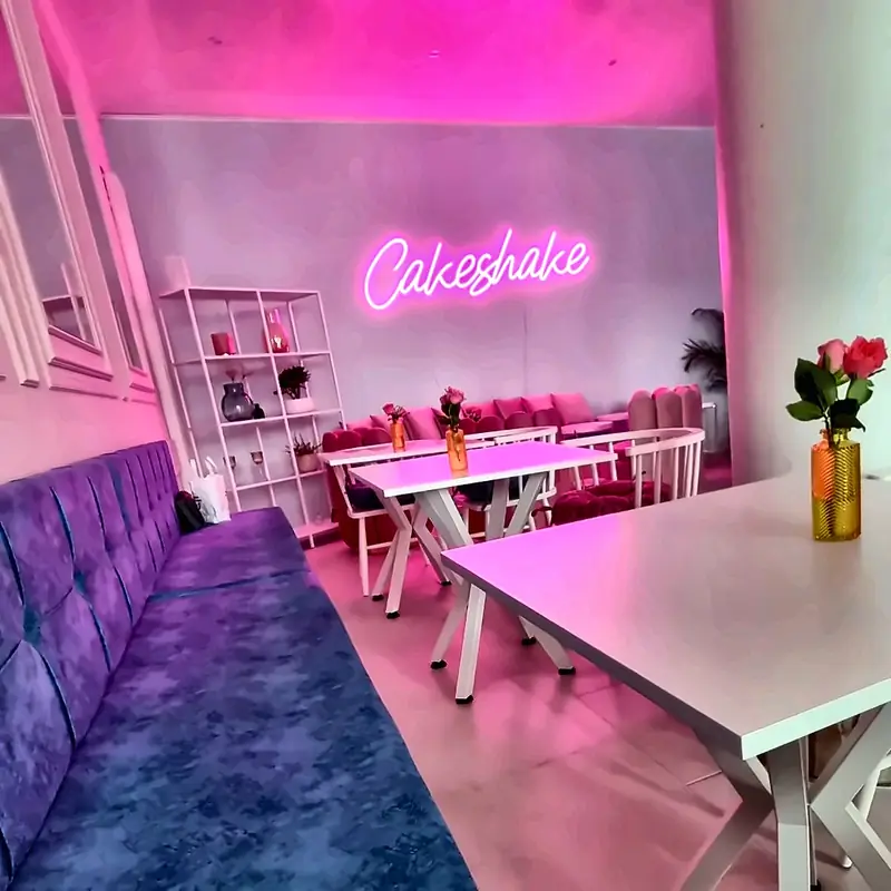 CakeShake von innen: rosa Neonschrift, Sitzecke und Tische
